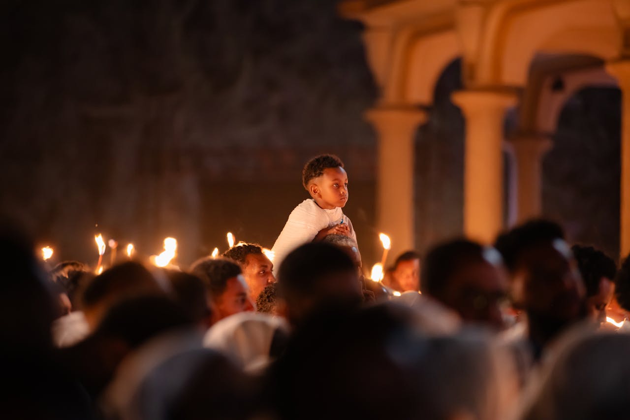 A boy on shoulders during a candlelit service at an Ethiopian church.